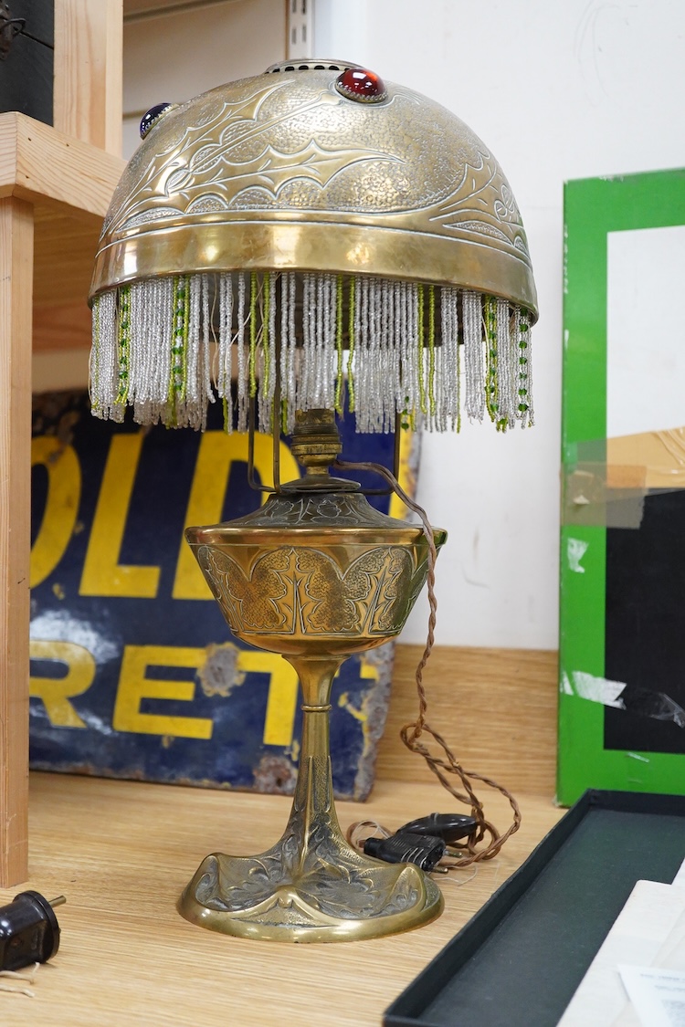 After Georges Leleu, an Art Nouveau brass oil lamp converted to electricity, with glass cabochon roundels and beaded fringing, 50cm high